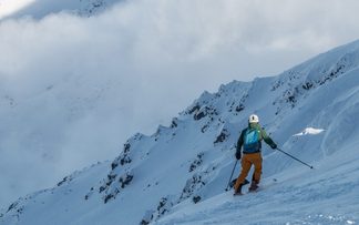 Skifahrer steht auf Piste im Hintergrund sind Berge