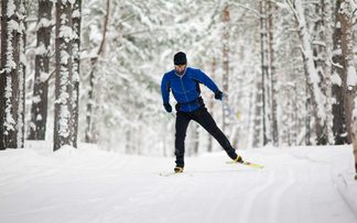 Langläufer fährt im Winter bei großer Kälte durch den verschneiten Wald.