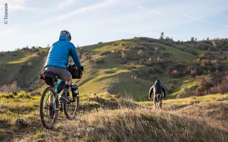 Gravelbiker mit Fahrradtaschen fährt durch die Natur