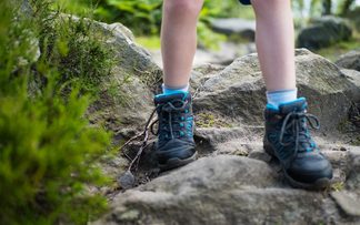 Kind wandert mit Kinderbergschuhen durch den Wald