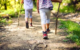 Zwei kleine Kinder auf Wanderweg mit Stöcken und Bergschuhen